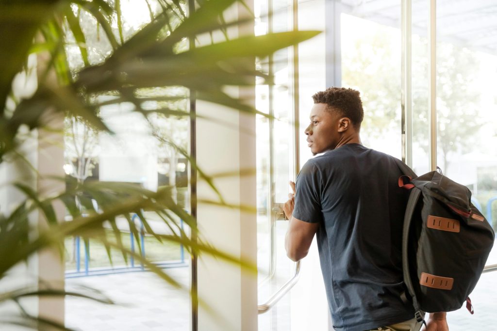 Young male student exiting university building